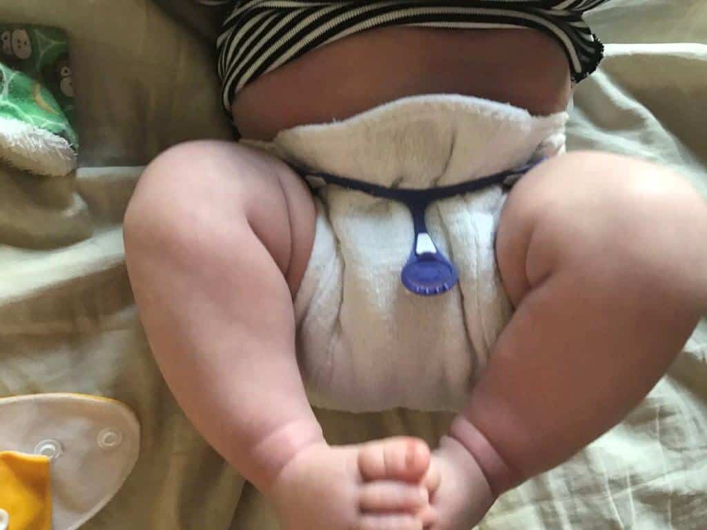 Wrap diaper around baby and use fastener to attach diaper